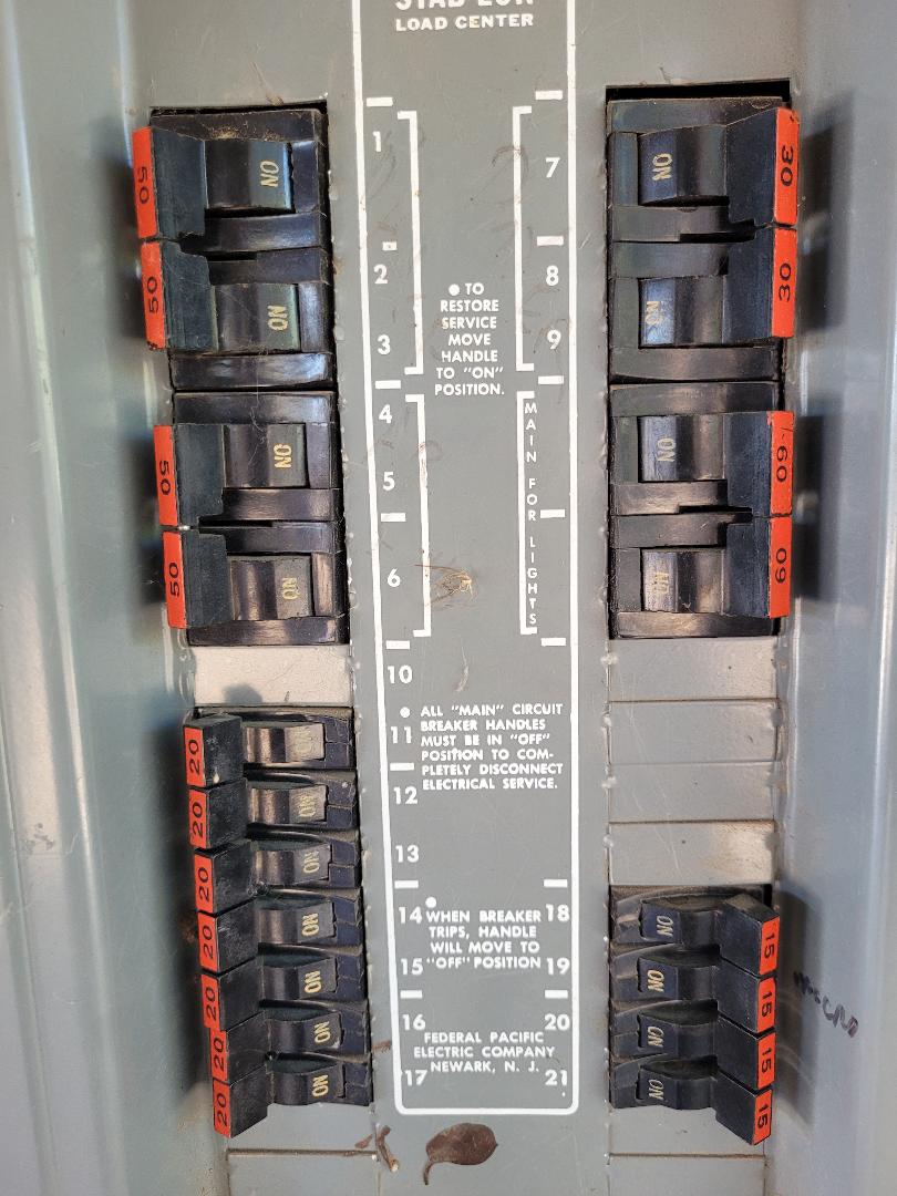 Open Federal Pacific Stab-Lok load center showing the characteristic red breaker tabs and Newark NJ FPE label