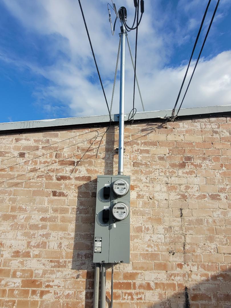 New Siemens dual-meter main installed on brick building with galvanized service mast